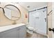 Modern bathroom featuring a gray vanity, round mirror, and a glass-enclosed shower with white tile at 7301 S Swoope St, Tampa, FL 33616