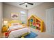 Bright and cheerful bedroom with a yellow bed frame, rainbow blanket, and house-shaped bookshelf at 7326 Blue Beech Dr, Riverview, FL 33578