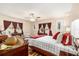 Bright main bedroom with wood floors, ceiling fan, and windows with red curtains at 8100 Roxboro Dr, Hudson, FL 34667