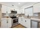 Modern kitchen featuring sleek white cabinets, stainless steel appliances, and a gray tile backsplash at 10847 Bounty St, New Port Richey, FL 34654