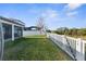View of the home's backyard with a white fence, screened porch, and lush lawn at 11432 Leland Groves Dr, Riverview, FL 33579