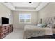 This main bedroom features a tray ceiling, soft carpet, and an elegant upholstered headboard at 11432 Leland Groves Dr, Riverview, FL 33579