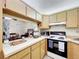 Kitchen featuring wood cabinets, white appliances, and a pass-through to the dining area at 1337 Pine Ridge E Cir # D2, Tarpon Springs, FL 34688