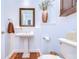 Cozy bathroom featuring white walls, hardwood floors, pedestal sink, and a toilet at 16318 Palmettoglen Ct, Lithia, FL 33547