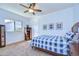 Cozy bedroom featuring a blue plaid bedspread, ceiling fan, and a window with natural light at 16318 Palmettoglen Ct, Lithia, FL 33547