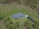 Aerial view of a charming home with a pool and well-maintained landscaping, surrounded by lush greenery at 17703 Country Squire Ln, Dade City, FL 33523