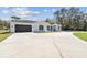 Charming single-story home with a two-car garage and large driveway, set against a backdrop of mature trees at 18214 Ozark Dr, Hudson, FL 34667