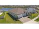 Aerial view of a modern residence with a spacious driveway, complemented by lush landscaping and a serene lake backdrop at 21396 Snowy Orchid Ter, Land O Lakes, FL 34637