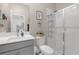 This bathroom features a white vanity, a framed mirror, and a tiled walk-in shower with glass doors at 21396 Snowy Orchid Ter, Land O Lakes, FL 34637