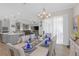 Open-concept dining room with elegant table setting, flowing curtains, and views to the kitchen and living room at 21396 Snowy Orchid Ter, Land O Lakes, FL 34637