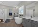 Main bathroom with soaking tub, walk-in shower, dual vanity, and wood look floor at 21396 Snowy Orchid Ter, Land O Lakes, FL 34637