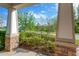 Covered porch featuring stone columns with verdant shrubbery and inviting view of the outdoors at 4127 Broad Porch Run, Land O Lakes, FL 34638