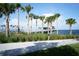 A tranquil waterfront view showing a pier, palm trees, a walking path, and green grass on a clear day at 4218 2Nd S Ave, St Petersburg, FL 33711