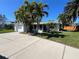 Charming single story home with white exterior, a lush lawn, and mature palms on a sunny day at 55 Dolphin Dr # A, Treasure Island, FL 33706