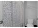 Toilet in neutral bathroom with gray and white flower-patterned shower curtain at 8780 Flourish Dr, Land O Lakes, FL 34637