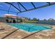 Swimming pool with blue water, and a screen enclosure overlooking the lake at 8780 Flourish Dr, Land O Lakes, FL 34637