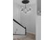 Modern light fixture illuminates the stairway with white banisters and neutral carpeting at 8780 Flourish Dr, Land O Lakes, FL 34637