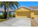 A sunlit, yellow garage door on a charming home with a well-maintained driveway and lush landscaping at 11422 Captiva Kay Dr, Riverview, FL 33569