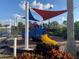 Community playground with a colorful train-themed play structure, sunshades, and lush landscaping at 11422 Captiva Kay Dr, Riverview, FL 33569