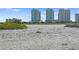 Expansive sandy beach with towering condominium buildings in the distance against a blue sky at 1180 Gulf Blvd # 1604, Clearwater Beach, FL 33767