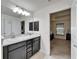 Bathroom featuring double sinks, a large mirror, and view into the main bedroom at 12220 Legacy Bright St, Riverview, FL 33578