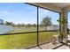 Spacious backyard with lush green grass, a white fence, a view of a lake, and a screened-in lanai at 12377 Streambed Dr, Riverview, FL 33579
