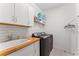 Well-lit laundry room featuring a sink, butcher block countertop, ample storage, and modern washer/dryer at 12377 Streambed Dr, Riverview, FL 33579