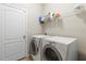 Clean laundry room with white washer and dryer, storage shelf and a closed door at 12919 Whittington Ct, Largo, FL 33773