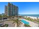 Towering beachfront condo building, featuring a pool, beach access, and tropical landscaping at 1480 Gulf Blvd # 401, Clearwater Beach, FL 33767