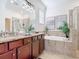 Bright bathroom featuring a double vanity with granite countertops, soaking tub, and tiled shower at 17533 Timberline Pkwy, Punta Gorda, FL 33982