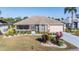 Beautifully landscaped front yard with lush shrubs, palm tree, screened porch, and attached garage at 2335 E Del Webb Blvd, Sun City Center, FL 33573