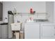 Functional laundry room featuring white washer, dryer, utility sink, and overhead shelving at 2335 E Del Webb Blvd, Sun City Center, FL 33573
