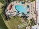 Aerial view of the community pool surrounded by ample lounge chairs, umbrellas, and lush landscaping at 2335 E Del Webb Blvd, Sun City Center, FL 33573