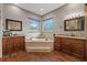Elegant bathroom features double vanities, a soaking tub, and stylish wood-look flooring at 27625 Lincoln Pl, Wesley Chapel, FL 33544