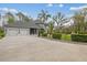 Long driveway leading to a gray home with a spacious two-car garage and lush landscaping at 27625 Lincoln Pl, Wesley Chapel, FL 33544