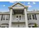 An inviting home showcasing stately columns, a charming balcony, and beautifully designed entryway with manicured shrubbery at 27625 Lincoln Pl, Wesley Chapel, FL 33544