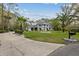 Wide view of the gray home featuring a circular driveway, fountain, and lush landscaping providing a welcoming entry at 27625 Lincoln Pl, Wesley Chapel, FL 33544