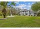 Expansive front lawn with lush green grass, a fountain, and mature trees surrounding a gray, two-story home at 27625 Lincoln Pl, Wesley Chapel, FL 33544