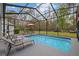 The inviting pool is surrounded by a screened enclosure, lounge chairs, and lush greenery at 27625 Lincoln Pl, Wesley Chapel, FL 33544