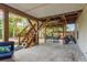 View of a covered backyard with outdoor furniture, a grill, and a wooden staircase at 314 Ontario Ave, Crystal Beach, FL 34681