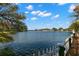 Scenic lake view featuring serene water, a white picket fence, and beautiful trees on a sunny day at 550 7Th S St, Safety Harbor, FL 34695