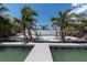 Beautiful backyard features a private pool, lush palm trees, and a white privacy fence at 575 Crystal Dr, Madeira Beach, FL 33708