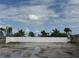 Vacant lot with white vinyl privacy fence and palm trees in the backyard at 575 Crystal Dr, Madeira Beach, FL 33708