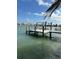 Wooden dock with a boat lift extends into the calm, turquoise waters of the bay at 575 Crystal Dr, Madeira Beach, FL 33708