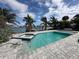 Backyard pool with spa and dock on a sunny day overlooking the water and palm trees at 575 Crystal Dr, Madeira Beach, FL 33708