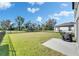 Large backyard features lush green lawn, mature trees, and a black grill on the patio at 9008 Waxwing Way, Parrish, FL 34219