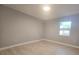 A neutrally painted bedroom with light tile flooring and a large window to the backyard at 9308 Pinero St, Spring Hill, FL 34608