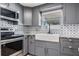 Updated kitchen features gray cabinets, stainless steel appliances, granite counters, and stylish backsplash at 10309 108Th Ave, Largo, FL 33773