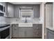 Updated kitchen features gray cabinets, granite counters, farmhouse sink, and stainless steel appliances at 10309 108Th Ave, Largo, FL 33773