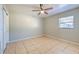 A bedroom with neutral paint, tile flooring, a ceiling fan, and natural light from the window at 10928 N 15Th St, Tampa, FL 33612